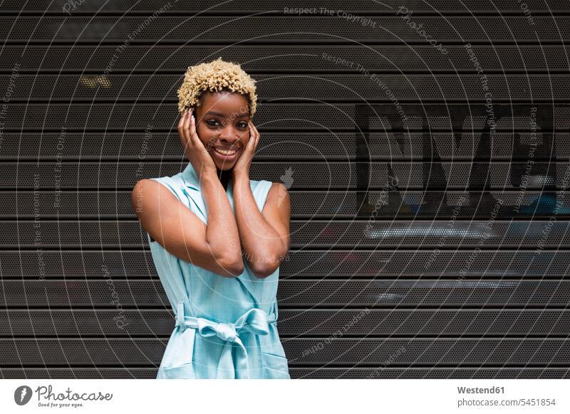 USA, New York, glückliche junge blonde afro-amerikanische Frau, lächelnd, Hand auf dem Kopf Afroamerikanisch Afro-Amerikanisch Afroamerikaner Afro-Amerikaner