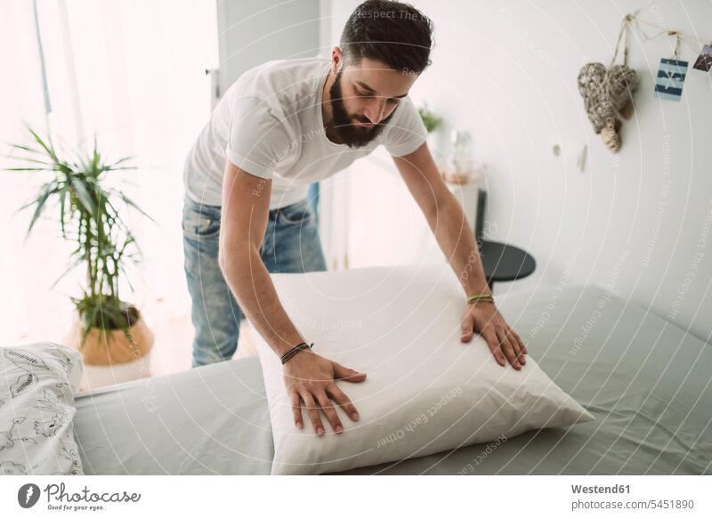 Junger Mann macht zu Hause das Bett Zuhause daheim Betten Männer männlich Erwachsener erwachsen Mensch Menschen Leute People Personen Europäer Kaukasier