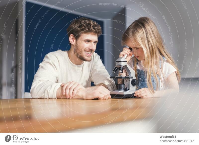 Vater beobachtet Tochter bei der Benutzung eines Mikroskops und lächelt stolz Stolz stolz sein spielen Mädchen weiblich lächeln clever schlau Mikroskope Papas