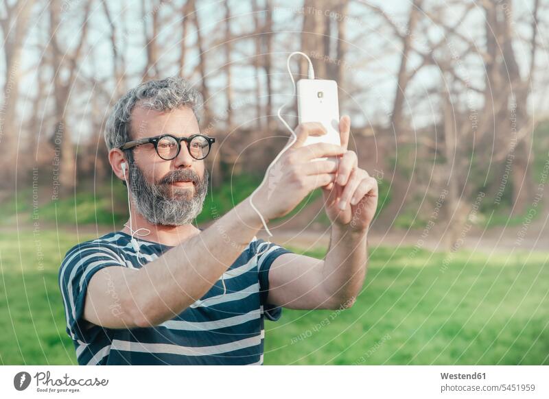 Bärtiger Mann macht Selfie mit Smartphone Selfies Männer männlich Portrait Porträts Portraits Erwachsener erwachsen Mensch Menschen Leute People Personen Brille