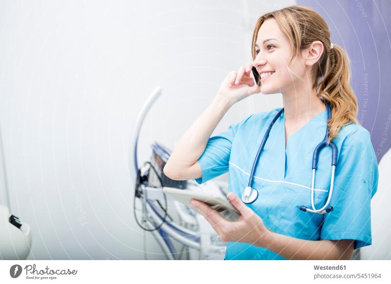 Lächelnder Arzt am Telefon hält Tablette Tablet Computer Tablet-PC Tablet PC iPad Tablet-Computer Frau weiblich Frauen lächeln Ärztin Aerztin Ärztinnen