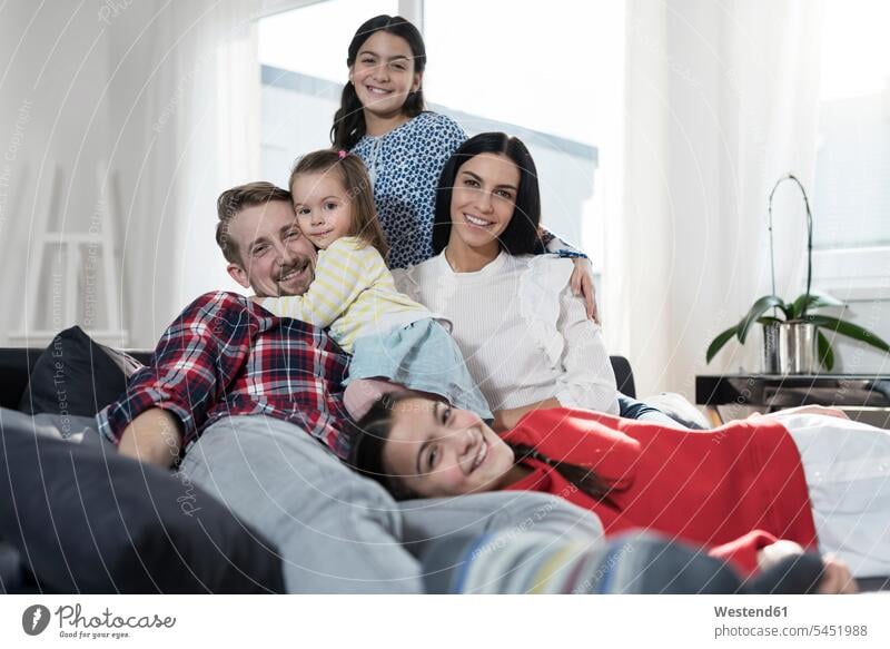 Porträt von Eltern und drei Töchtern auf dem Sofa im Wohnzimmer Couches Liege Sofas Familie Familien lächeln Tochter Mensch Menschen Leute People Personen Kind