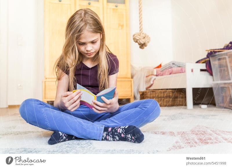 Mädchen sitzt auf dem Boden des Kinderzimmers und liest ein Buch lesen Lektüre weiblich Bücher Kids Mensch Menschen Leute People Personen sitzen sitzend