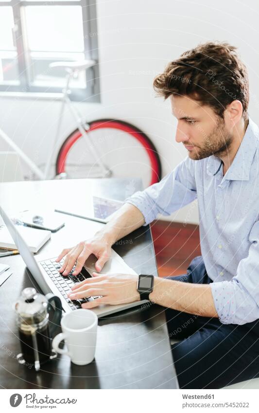 Junger Geschäftsmann, der im Büro arbeitet und einen Laptop benutzt Smartwatch Kaffee tippen Notebook Laptops Notebooks Businessmann Businessmänner