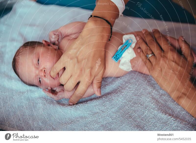 Neugeborenes Mädchen liegt auf einem Handtuch und saugt am Finger der Mutter Hände Baby Babies Babys Säuglinge Kind Kinder Mensch Menschen Leute People Personen