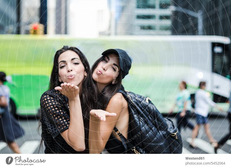 USA, New York City, zwei Zwillingsschwestern blasen sich in Manhattan einen Kuss zu Schwester Schwestern New York State Freundinnen Spaß Spass Späße spassig