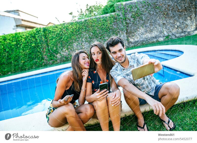 Freunde machen ein Selfie am Pool Handy Mobiltelefon Handies Handys Mobiltelefone lächeln Swimmingpool Swimmingpools Schwimmbecken Swimming Pool Swimming Pools
