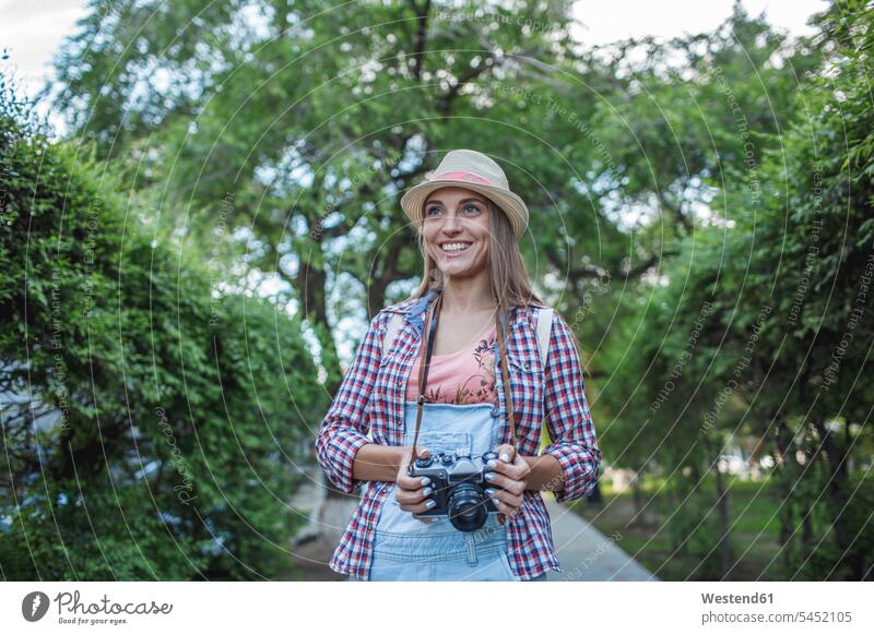 Lächelnde junge Frau mit einer Kamera in einem Park Fotoapparat Fotokamera lächeln Parkanlagen Parks weiblich Frauen Erwachsener erwachsen Mensch Menschen Leute