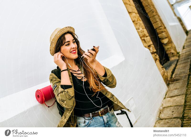 Lächelnde junge reisende Frau benutzt Mobiltelefon Handy Handies Handys Mobiltelefone sprechen reden weiblich Frauen Telefon telefonieren Kommunikation