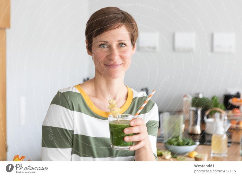 Porträt einer lächelnden Frau mit grünem Smoothie in der Küche Portrait Porträts Portraits weiblich Frauen Smoothies Erwachsener erwachsen Mensch Menschen Leute