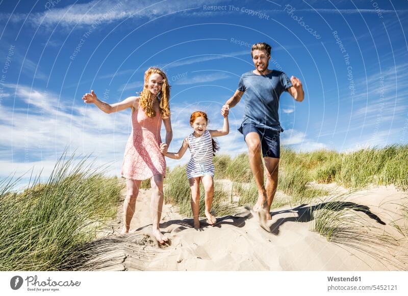 Niederlande, Zandvoort, glückliche Familie mit Tochter, die in Stranddünen läuft Glück glücklich sein glücklichsein Spaß Spass Späße spassig Spässe spaßig