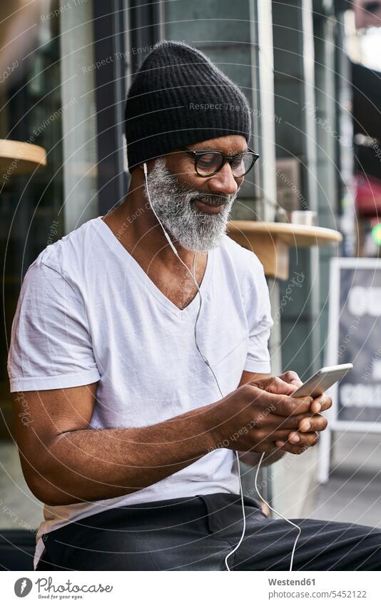 Reifer Mann benutzt Smartphone im Café Geschäftsmann Businessmann Businessmänner Geschäftsmänner SMS Textnachricht lesen Lektüre unterwegs auf Achse in Bewegung