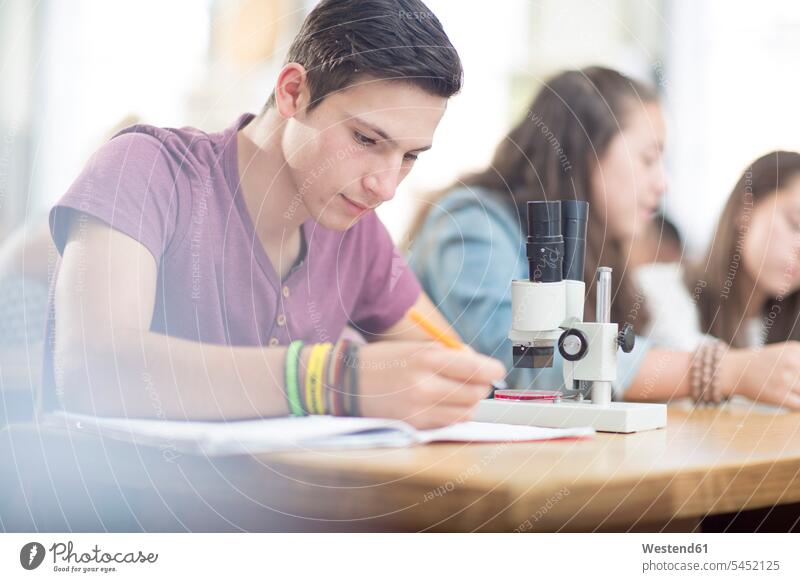 Studenten der Naturwissenschaften arbeiten im Unterricht mit dem Mikroskop schreiben aufschreiben notieren schreibend Schrift Mikroskope lernen Schüler Bildung
