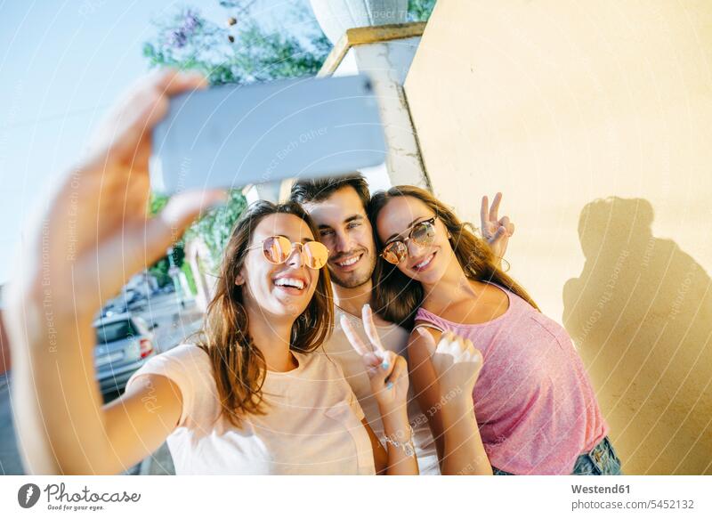 Freunde machen ein Selfie mit Smartphone auf der Straße Handy Mobiltelefon Handies Handys Mobiltelefone Selfies Spaß Spass Späße spassig Spässe spaßig lachen