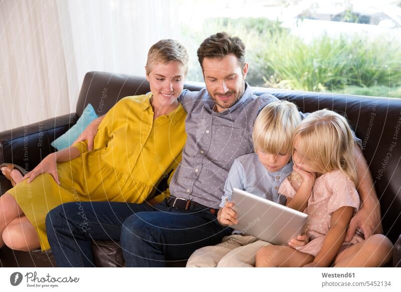 Familie sitzt zu Hause auf der Couch mit tablet sitzen sitzend Tablet Tablet Computer Tablet-PC Tablet PC iPad Tablet-Computer Zuhause daheim Familien benutzen