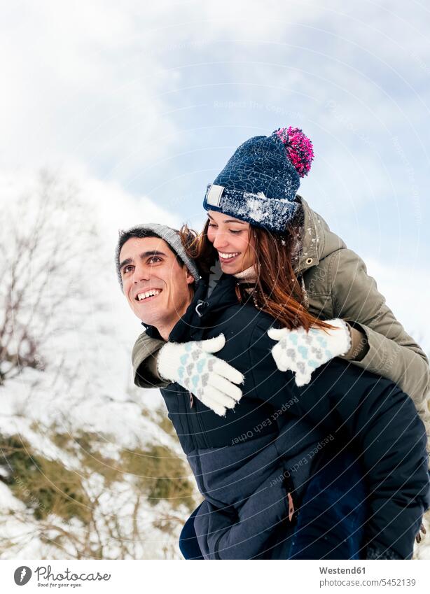 Junger Mann trägt sein Mädchen im Winter huckepack gebraten Freundschaft Freunde Kameradschaft Schnee lachen frisch verliebt sich verlieben winterlich