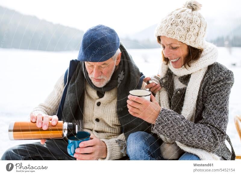 Älteres Ehepaar macht eine Pause mit heißen Getränken in verschneiter Winterlandschaft Seniorenpaar älteres Paar Seniorenpaare ältere Paare Seniorenpärchen