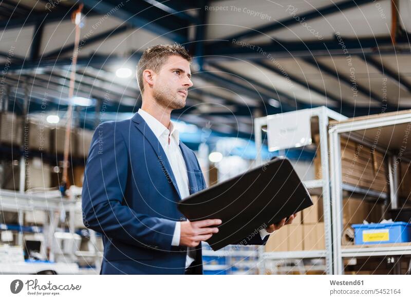 Porträt eines jungen Managers in der Werkstatt, der eine Akte hält stehen stehend steht Inventur Unternehmen Firma Dokument Dokumente Papiere Unterlagen