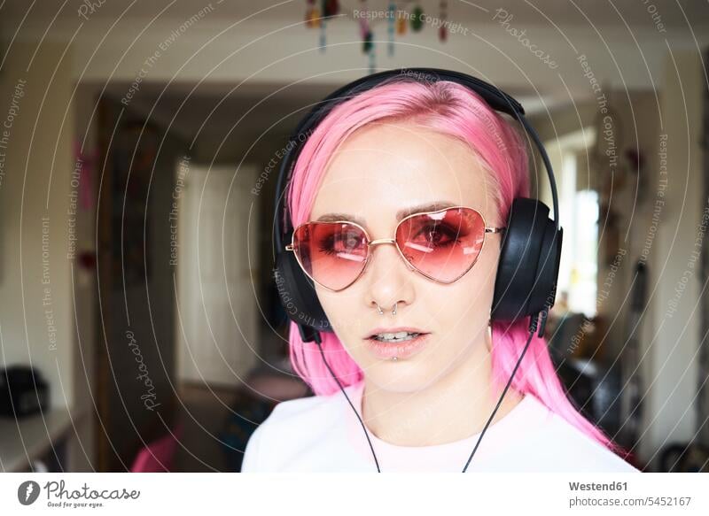 Porträt einer jungen Frau mit rosa Haaren und herzförmiger Sonnenbrille beim Musikhören Brille Brillen weiblich Frauen Portrait Porträts Portraits Kopfhörer