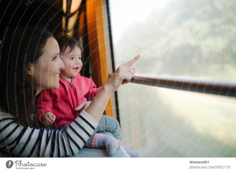 Glückliche Mutter und kleines Mädchen, die mit dem Zug reisen und aus dem Fenster schauen Baby Babies Babys Säuglinge Kind Kinder zeigen mit dem Finger zeigen