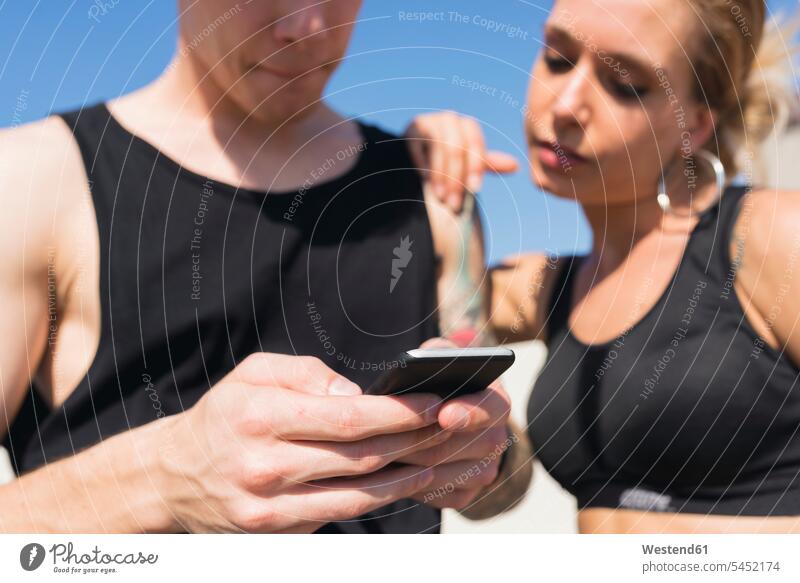 Junges Paar schaut auf Handy, Nahaufnahme Smartphone iPhone Smartphones Hände Mobiltelefon Handies Handys Mobiltelefone Telefon Kommunikation Telekommunikation