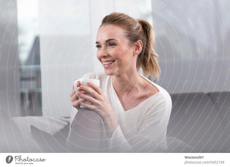 Porträt einer glücklichen Frau mit Kaffeebecher zu Hause weiblich Frauen Zuhause daheim Becher Glück glücklich sein glücklichsein Erwachsener erwachsen Mensch
