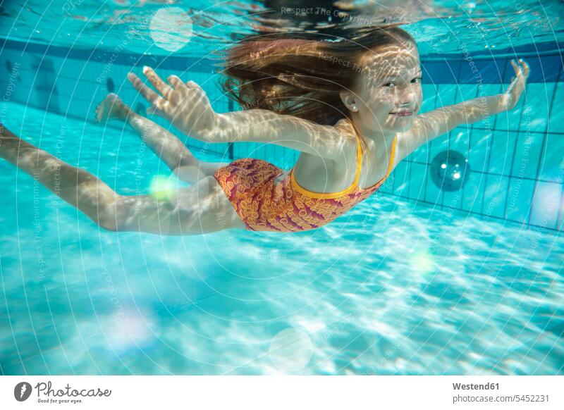 Porträt eines lächelnden Mädchens, das im Schwimmbad unter Wasser schwimmt Portrait Porträts Portraits Unterwasser Unterwasseraufnahme Unterwasserfoto schwimmen