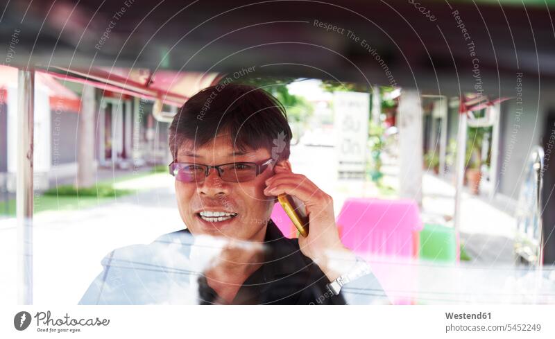 Thailand, Bangkok, Tuk-Tuk-Fahrer telefoniert Smartphone iPhone Smartphones telefonieren anrufen Anruf telephonieren Unterhaltung Gespraech Gespräch Gespraeche