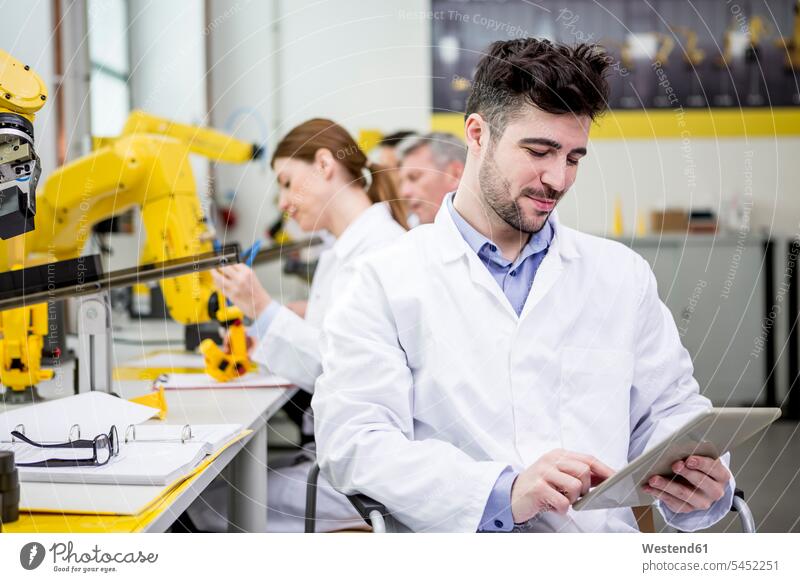Ingenieur, der ein Tablett mit Industrierobotern im Hintergrund hält Tablet Computer Tablet-PC Tablet PC iPad Tablet-Computer Ingenieure Fabrik Fabriken Rechner