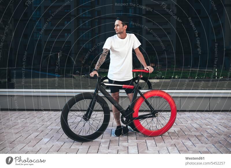 Junger Mann mit Fixie-Rad in der Stadt stehen stehend steht Fahrrad Bikes Fahrräder Räder Männer männlich Raeder Erwachsener erwachsen Mensch Menschen Leute