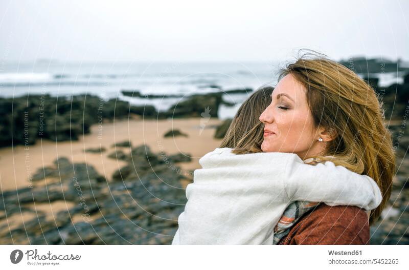 Mutter hält Tochter im Winter am Strand Beach Straende Strände Beaches glücklich Glück glücklich sein glücklichsein Töchter lächeln Mami Mutti Mütter Mama Kind