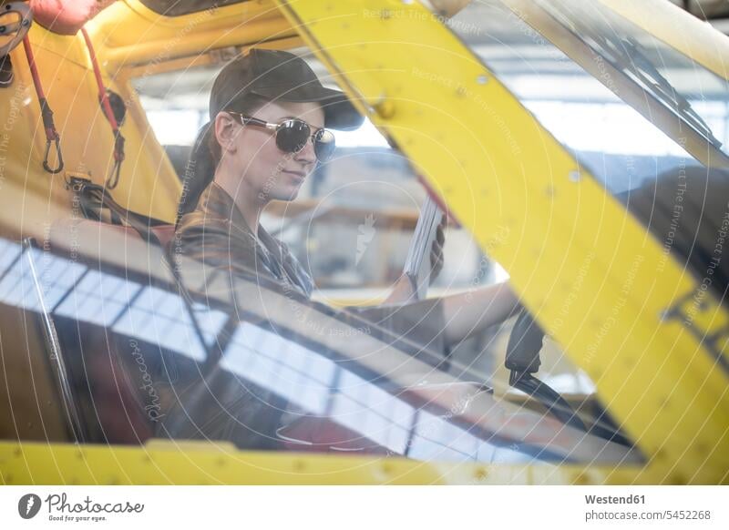 Weibliche Pilotin inspiziert Leichtflugzeug-Cockpit sitzen sitzend sitzt überprüfen testen checken Kleinflugzeug Pilotinnen Flugzeug Flieger Flugzeuge