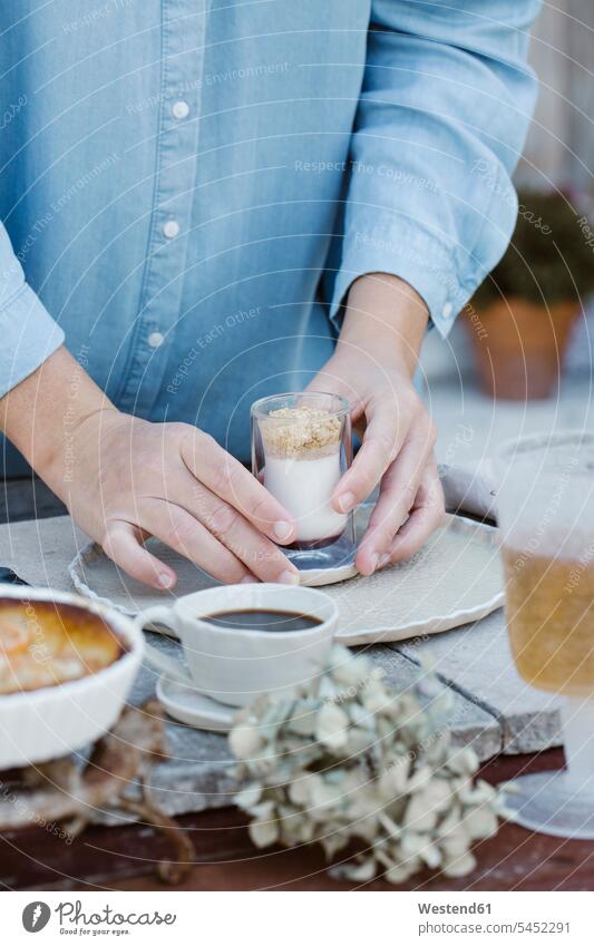 Italien, Frau arrangiert ein Glas Dessert auf dem Frühstückstisch, Teilansicht frühstücken Tisch Tische Terrasse Terrassen Hand Hände Nachspeise Desserts
