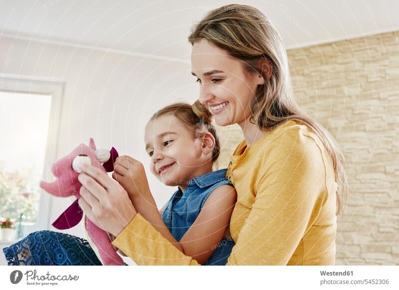 Glückliche Mutter und Tochter spielen zu Hause mit Kuscheltier Stofftier Stofftiere Töchter lächeln glücklich glücklich sein glücklichsein Mami Mutti Mütter