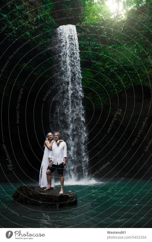 Zärtliches älteres Ehepaar steht vor einem tropischen Wasserfall attraktiv schoen gut aussehend schön Attraktivität gutaussehend hübsch Wasserfälle Wasserfaelle