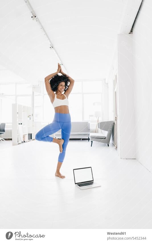 Junge Frau praktiziert Yoga mit Laptop an ihrer Seite Online Training trainieren fit weiblich Frauen üben ausüben Übung Notebook Laptops Notebooks lernen