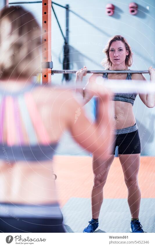 Junge Frau hebt Langhantel im Fitnessstudio trainieren Fitnessclubs Fitnessstudios Turnhalle weiblich Frauen Gewichtheben fit Gesundheit gesund Sport