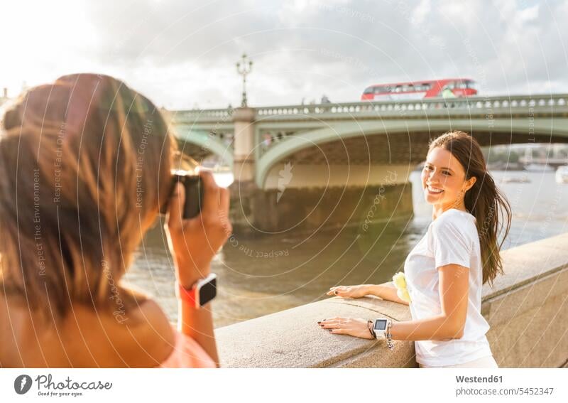 UK, London, Frau, die in der Nähe der Westminster Bridge ein Foto von ihrem Freund macht Fotoapparat Kamera Fotokamera lächeln fotografieren Freundinnen