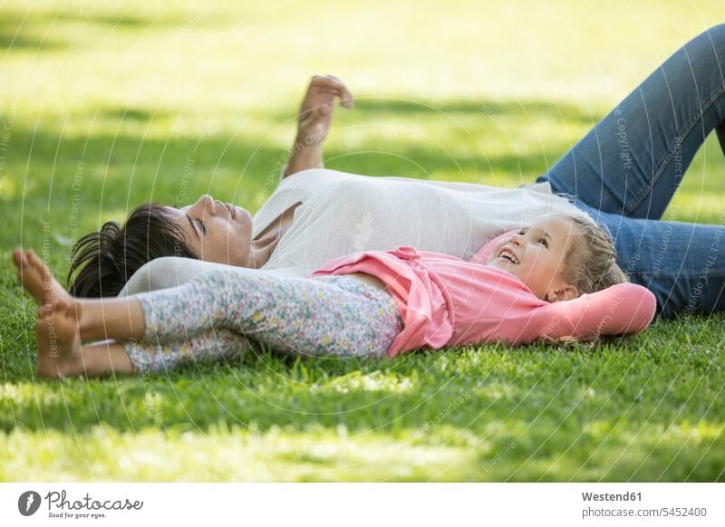 Mutter und Tochter im Gras liegend lächeln Töchter glücklich Glück glücklich sein glücklichsein Mami Mutti Mütter Mama Wiese Wiesen entspannt entspanntheit