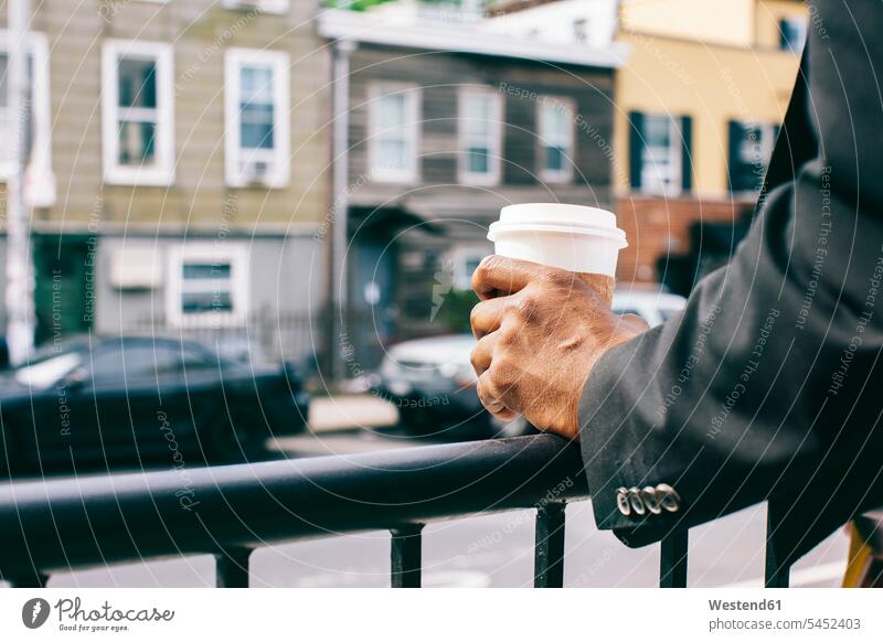 Hände eines Mannes, der eine Tasse Kaffee an einem Geländer hält hip trendy cool Coolness Brooklyn Männer männlich Getränk Getraenk Getränke Getraenke