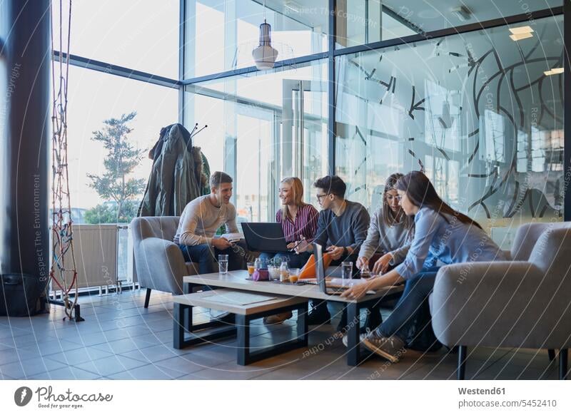 Gruppe von Freunden sitzt zusammen in einem Café mit Laptop und Getränken Cafe Kaffeehaus Bistro Cafes Cafés Kaffeehäuser sitzen sitzend Gemeinsam Zusammen