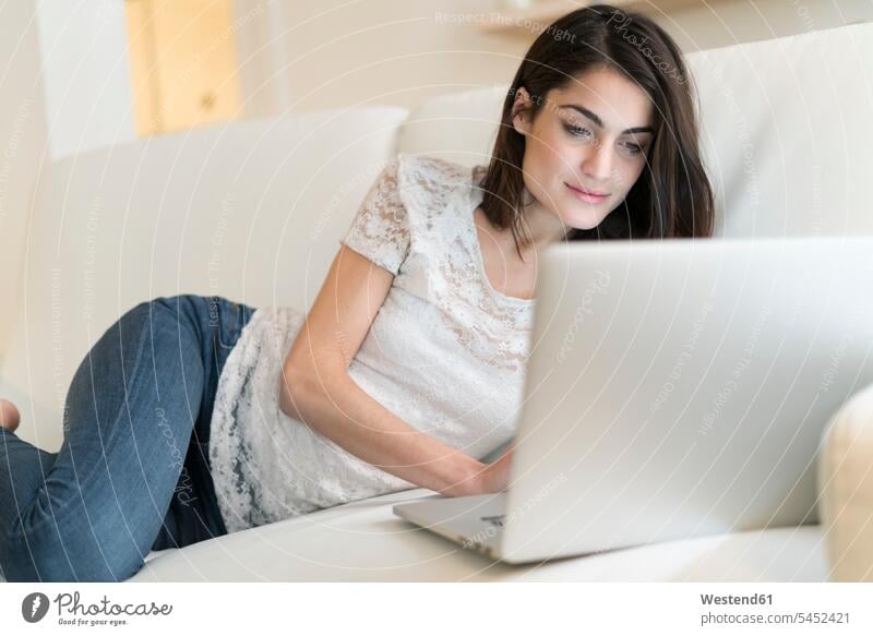 Porträt einer Frau auf Couch mit Laptop Notebook Laptops Notebooks Sofa Couches Liege Sofas weiblich Frauen Computer Rechner Erwachsener erwachsen Mensch