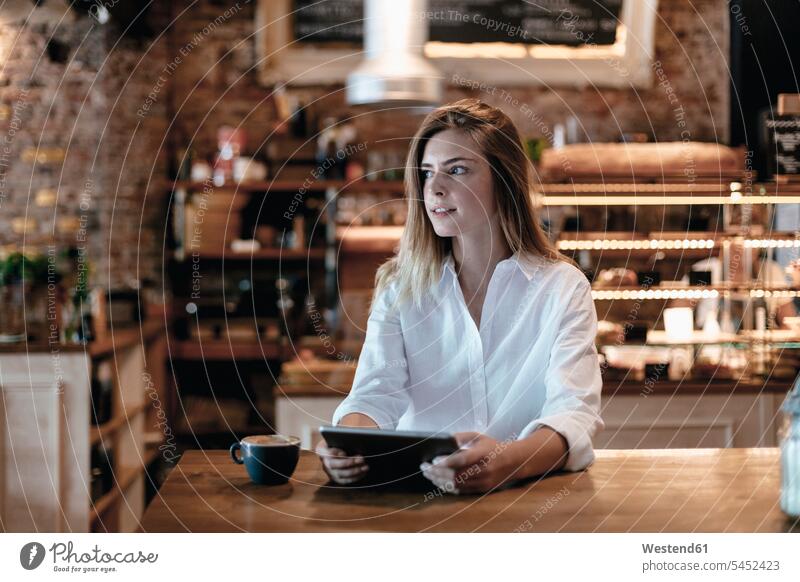 Blonde Frau sitzt im Café, benutzt Tabletten, denkt Tablet Computer Tablet-PC Tablet PC iPad Tablet-Computer Cafe Kaffeehaus Bistro Cafes Cafés Kaffeehäuser