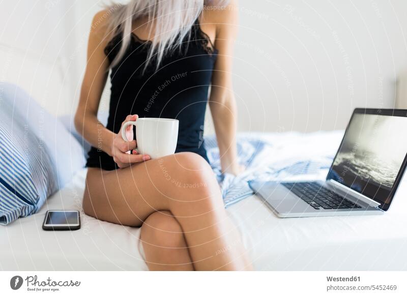 Junge Frau im Bett mit Tasse Kaffee und Laptop Notebook Laptops Notebooks Kaffeetasse Kaffeetassen weiblich Frauen Betten Getränk Getraenk Getränke Getraenke