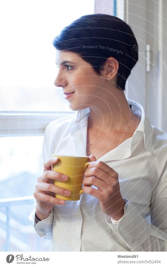 Frau hält Tasse Kaffee und schaut aus dem Fenster lächeln weiblich Frauen Getränk Getraenk Getränke Getraenke Food and Drink Lebensmittel Essen und Trinken