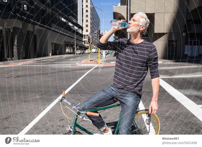 Mann auf Fahrrad Trinkwasser Stadt staedtisch städtisch unterwegs auf Achse in Bewegung Bikes Fahrräder Räder Rad radfahren fahrradfahren radeln trinken Männer