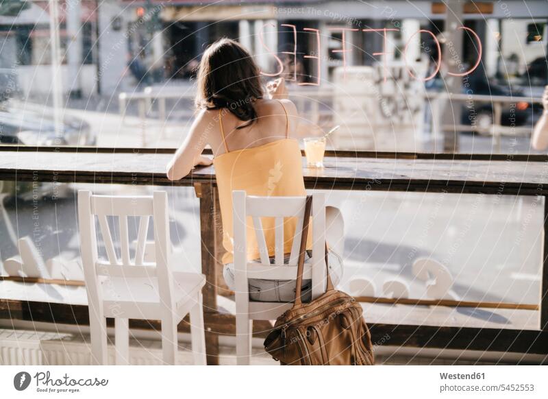 Frau sitzt im Cafe und schreibt das Wort "Kaffee" auf die Fensterscheibe Lippenstift Lippenstifte zeichnen Zeichnung schreiben aufschreiben notieren schreibend