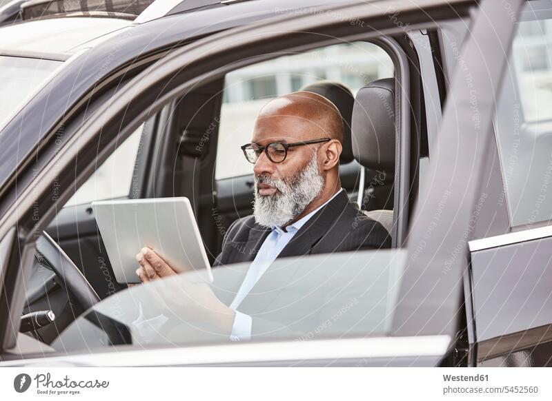 Geschäftsmann sitzt im Auto und benutzt digitales Tablet Tablet Computer Tablet-PC Tablet PC iPad Tablet-Computer unterwegs auf Achse in Bewegung Businessmann