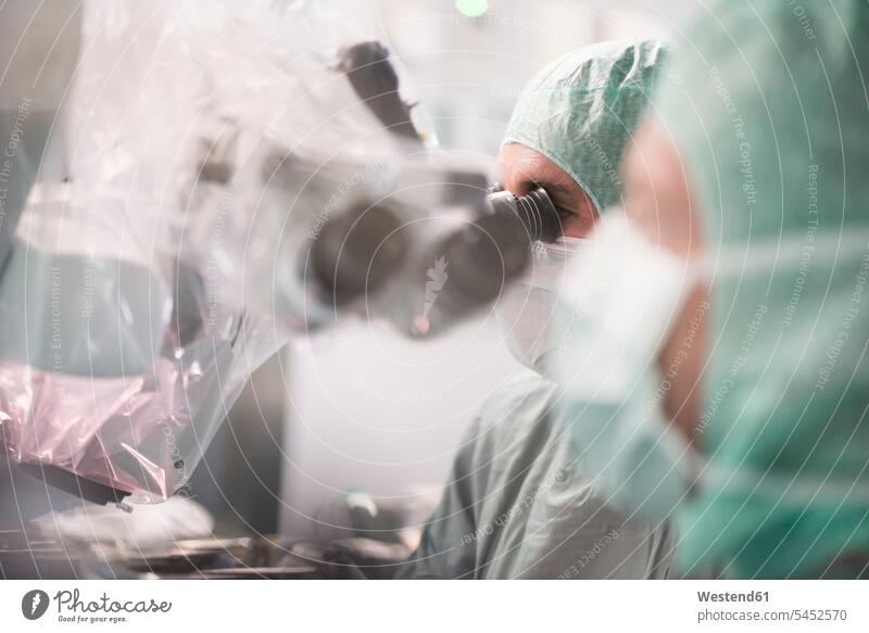 Neurochirurg, der während einer Operation durch ein Mikroskop schaut OP Operationen operieren Chirurgie Arzt Doktoren Ärzte Behandlung Krankenbehandlung