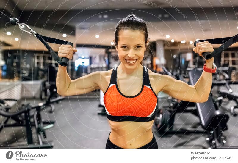 Porträt einer glücklichen jungen Frau, die im Fitnessstudio trainiert trainieren weiblich Frauen Fitnessclubs Fitnessstudios Turnhalle lächeln Erwachsener